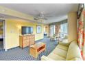 Open living room with couch, armchairs, a tv and access to bedroom and balcony at 5300 N Ocean Blvd. # 923, Myrtle Beach, SC 29577
