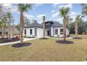 Striking home features a white exterior with black accents, landscaped yard, and inviting walkway to the front door at 1559 Old Tram Rd., Little River, SC 29566