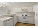 Efficient kitchen featuring white cabinets, countertops and appliances and a wood floor at 2000 Cross Gate Blvd. # 104, Surfside Beach, SC 29575