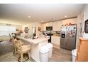Open kitchen with white cabinetry, stainless steel appliances, and a breakfast bar overlooking the dining area at 203 Golden Bear Circle, Longs, SC 29568