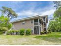 Rear view of condo featuring outdoor living space with screened-in porches and lush landscaping at 227 Pinehurst Ln. # 6D, Pawleys Island, SC 29585