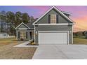 Charming home exterior at dusk featuring a two-car garage, landscaped front yard, and green siding at 4010 Macks Rd, Aynor, SC 29511