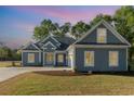 Charming single-story home with blue siding, white trim, and well-manicured lawn at twilight at 4022 Macks Rd, Aynor, SC 29511