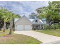 Inviting two-story home featuring a two-car garage, metal roof, manicured lawn and a covered porch at 521 Oak Lawn Rd., Georgetown, SC 29440