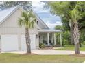 Inviting two-story home featuring a two-car garage, metal roof, manicured lawn and a covered porch at 521 Oak Lawn Rd., Georgetown, SC 29440