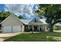 Inviting two-story home featuring a two-car garage, metal roof, manicured lawn and a covered porch at 521 Oak Lawn Rd., Georgetown, SC 29440