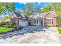 Lovely brick home featuring an attached garage, manicured lawn, and a charming front porch with classic architectural details at 5647 S Blackmoor Dr., Murrells Inlet, SC 29576