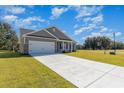 A single-story home featuring a long driveway, well-maintained lawn, a gray exterior with a white garage door at 108 Old Chimney Ln, Conway, SC 29526