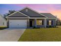 Charming single-story home at sunset with a two-car garage, brick accents, manicured lawn, and beautiful curb appeal at 108 Old Chimney Ln, Conway, SC 29526