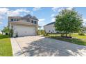 Exterior view showing a large driveway leading to a well-maintained two-story home with lush landscaping at 1313 Cascarilla Ct., Myrtle Beach, SC 29579
