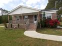 Inviting brick home with a covered porch, complemented by a well-kept lawn and red flower accents at 1465 Dirty Branch Rd., Conway, SC 29527