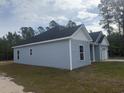 Side view of blue house featuring white windows, a black roof, and a well-maintained lawn at 10522 W Highway 19, Loris, SC 29569
