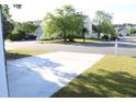 A view of the street with a long driveway, green grass, trees, utility vehicles, and houses in the background at 148 Weeping Willow Dr., Myrtle Beach, SC 29579