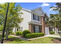 Charming brick and vinyl-sided townhome with manicured landscaping, walkway, mature trees and black shutters at 220 Connemara Dr. # A, Myrtle Beach, SC 29579