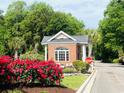 Brick-built gatehouse at the entrance of the community, surrounded by lush greenery and vibrant red flowers at 4482 Fringetree Dr., Murrells Inlet, SC 29576
