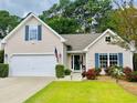 Inviting one-story home featuring a well-kept lawn, pops of red flowers, and a two-car garage at 4482 Fringetree Dr., Murrells Inlet, SC 29576