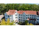 Exterior view of a bright, multi-story condo building with white balconies and red roofing at 4601 Greenbriar Dr. # 201, Little River, SC 29566