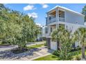 Beautiful two-story home with double garage and balcony, complemented by lush greenery at 48 Half Shell Ct., Litchfield, SC 29585