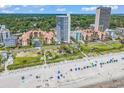 Stunning aerial view of an oceanfront condo with lush landscaping, a white sandy beach, and vibrant blue ocean at 5511 N Ocean Blvd. # 209, Myrtle Beach, SC 29577