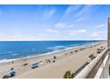 Picturesque beach view from a condo balcony showcasing the ocean, shoreline and people enjoying the sand and surf at 1012 N Waccamaw Dr. # 507, Murrells Inlet, SC 29576