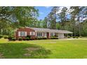 Beautiful brick home with white-trimmed windows, landscaped shrubs, and a spacious green lawn at 2192 Highway 308, Galivants Ferry, SC 29544