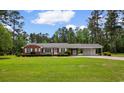 Picture of cozy brick home on a lush green lawn, shaded by mature trees and a bright blue sky at 2192 Highway 308, Galivants Ferry, SC 29544