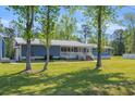 Charming exterior view of a home with a covered porch, lovely trees and lush green lawn at 3759 Cypress Dr., Little River, SC 29566