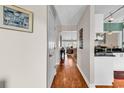 View of the home's hallway with hardwood flooring connecting to a dining and living area with lots of natural light at 4755 Lightkeepers Way # 15-E, Little River, SC 29566