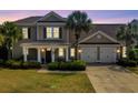 Charming home exterior with a two-car garage, inviting front porch, landscaped yard, and mature palm trees at dusk at 546 Olde Mill Dr., North Myrtle Beach, SC 29582