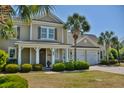 Lovely home with a welcoming porch, manicured landscaping, and an attached two-car garage framed by beautiful palm trees at 546 Olde Mill Dr., North Myrtle Beach, SC 29582