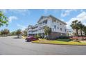 Condo building with multi-level balconies, parking, and landscaped grounds under a sunny sky at 5750 Oyster Catcher Dr. # 234, North Myrtle Beach, SC 29582
