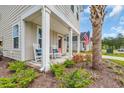 Charming front porch showcasing classic white rocking chairs and lush landscaping, enhancing curb appeal at 9012 Mabel Ct., Longs, SC 29568