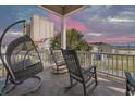 Relaxing covered balcony with rocking chairs and hanging swing offering scenic neighborhood views at 1718 Perrin Dr., North Myrtle Beach, SC 29582