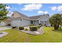 Well-maintained home with manicured lawn, mature landscaping, and an attached garage at 207 Cupola Dr., Longs, SC 29568