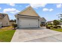 Attached two-car garage with a clean driveway and manicured landscaping at 207 Cupola Dr., Longs, SC 29568