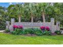 Beautiful stone entrance to Coquina Harbour with vibrant flowers and mature palm trees on a manicured lawn at 4215 Coquina Harbour Dr. # D -2, Little River, SC 29566