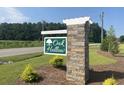 Stone monument sign for Oak Hollow, a new home community on a green lawn with a road and trees at 958 Oak Hollow St., Longs, SC 29568