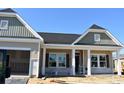 New construction with a two-car garage, covered front porch, beige siding and black roof at 962 Oak Hollow St., Longs, SC 29568