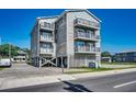 Three-story condo building on stilts with a large concrete parking pad and private balconies at 1208 S Ocean Blvd. # H, North Myrtle Beach, SC 29582