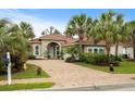 Home exterior with a brick driveway and a tile roof amidst lush, tropical landscaping at 216 Northside Dr., Little River, SC 29566