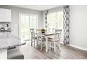 Bright dining area with a white table, six chairs, and sliding doors for outdoor access at 3208 Nw Edgemead Circle # B, Calabash, NC 28467