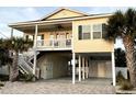 Elevated beach house featuring a covered porch, exterior staircase, and covered parking area at 412 29Th Ave. N, North Myrtle Beach, SC 29582