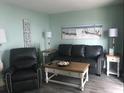A nicely decorated living room features a sofa, recliner, beach-themed artwork, and side tables at 5905 S Kings Hwy. # 314-B, Myrtle Beach, SC 29575