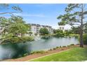 Scenic view of a tranquil pond with fountain, surrounded by mature trees and condo buildings at 601 Hillside Dr. N # 1405, North Myrtle Beach, SC 29582