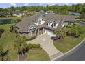 Sprawling brick home with lush landscaping, private pond, and a lengthy driveway, captured from an aerial perspective at 63 Grey Moss Rd., Murrells Inlet, SC 29576