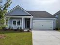 Inviting single-story home featuring a covered porch, attached garage and manicured front lawn at 2026 Lone Cypress Dr, Myrtle Beach, SC 29579