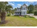 Beautiful two-story home with a covered porch, lush green lawn, and a white picket fence at 221 Lander Dr., Conway, SC 29526
