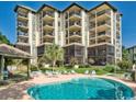 Multi-story condominium with poolside patio, lounge chairs, a pool and screened in porch at 310 N 73Rd Ave. N # 5D, Myrtle Beach, SC 29572