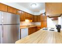 Compact kitchen featuring stainless steel refrigerator, white dishwasher, and wood-grain cabinets and countertops at 404 75Th Ave N # G, Myrtle Beach, SC 29572