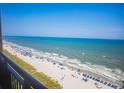 Stunning ocean view from balcony, with a sandy beach filled with people and beach umbrellas on a beautiful day at 4800 S Ocean Blvd. # 1402, North Myrtle Beach, SC 29582